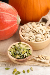 Bowls with seeds and fresh pumpkins on light wooden table