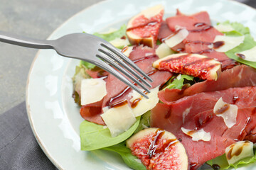 Eating delicious bresaola salad at grey table, closeup