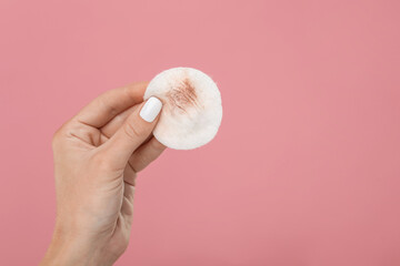 Woman with dirty cotton pad after removing makeup on pink background, closeup. Space for text © New Africa