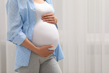 Pregnant woman indoors, closeup. Space for text