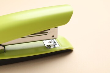 One bright stapler on beige background, closeup. Space for text