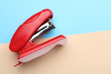 One red stapler on color background, top view. Space for text