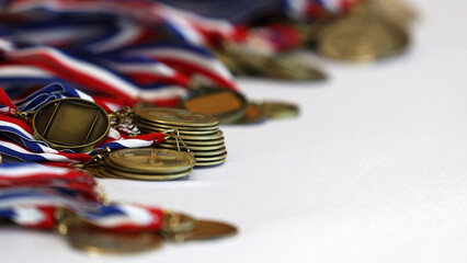 A large pile of participation or winners medals on red white and blue ribbons laying on a white...