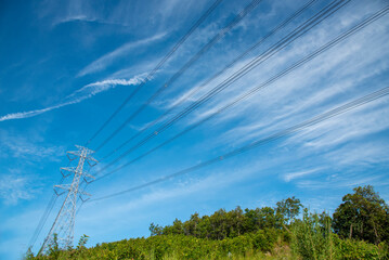 High voltage pole electric wiring distribution landscape energy engineering. Electricity energetic background with blue sky green mountain in countryside. Electric power energy engineering industrial