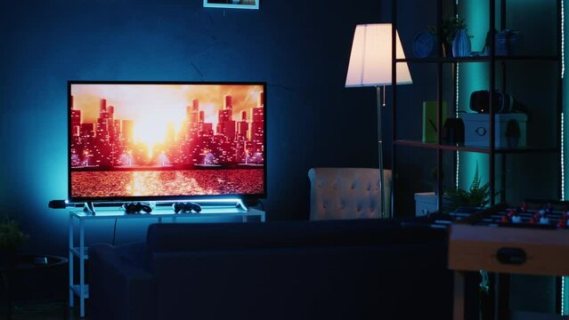 Empty stylish neon lit home studio interior illuminated with neon lights at night and artwork decorating the walls. Modern apartment with TV running in background on news channel broadcast