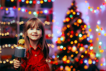 Happy Girl Holding a Microphone Singing Carols. Cheerful child performing Christmas songs for her...