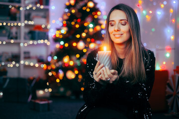 Happy Woman Holding a Candle Celebrating Christmas at Home. Adult person feeling festive enjoying holiday atmosphere
