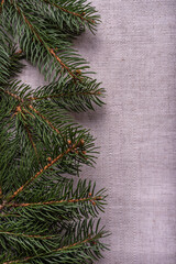 Natural spruce coniferous green branches with two white candles in candlesticks in the form of cones on a grey linen tablecloth background. Festive decoration of the Christmas table. Top view.