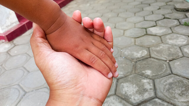 son holding mother's hand outdoors, closeup. Happy family