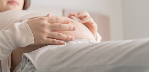 Obraz na płótnie Canvas Pregnant woman holds hands on belly touching her baby caring about her health Beautiful happy pregnant woman .tender mood photo of pregnancy.