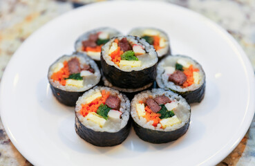 kimbap making, a cherished Korean culinary tradition. Skilled hands roll rice, vegetables, and seaweed, crafting delicious, nutritious bites for an authentic dining experience