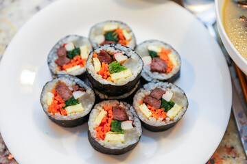 kimbap making, a cherished Korean culinary tradition. Skilled hands roll rice, vegetables, and seaweed, crafting delicious, nutritious bites for an authentic dining experience