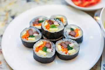 kimbap making, a cherished Korean culinary tradition. Skilled hands roll rice, vegetables, and seaweed, crafting delicious, nutritious bites for an authentic dining experience