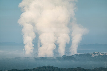 Fototapeta premium Beautiful morning scenery with fog in the background at Mae Moh Lignite Coal Power Plant, Lampang, Thailand Industrial white vapor from cooling and tower pipes, concept industrial environment