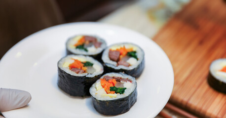 kimbap making, a cherished Korean culinary tradition. Skilled hands roll rice, vegetables, and seaweed, crafting delicious, nutritious bites for an authentic dining experience