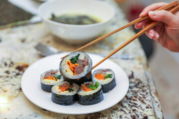 kimbap making, a cherished Korean culinary tradition. Skilled hands roll rice, vegetables, and seaweed, crafting delicious, nutritious bites for an authentic dining experience