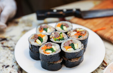 kimbap making, a cherished Korean culinary tradition. Skilled hands roll rice, vegetables, and seaweed, crafting delicious, nutritious bites for an authentic dining experience