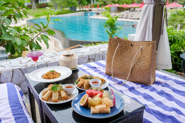 lunch at a restaurant looking out over the swimming pool, and dinner in a restaurant by the pool in Pattaya Thailand. snacks and spaghetti on a table - obrazy, fototapety, plakaty