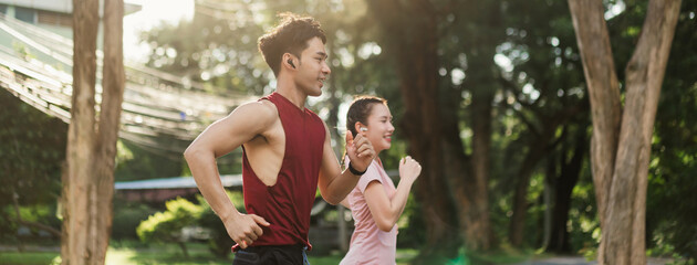 Two Asian young athlete man and woman in sportswear jogging exercise in park outdoor. Together young couple running outdoor in the morning. Healthy exercise concept. - obrazy, fototapety, plakaty