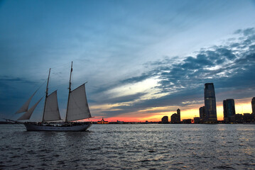 A Schooner Sailing through Hudson River at Dusk with Jersey City Skyline in the Background - New...