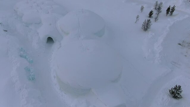 Drone view on the Tromso mountains in winter full of snow showing an igloo shaped ice hotel from above in Norway