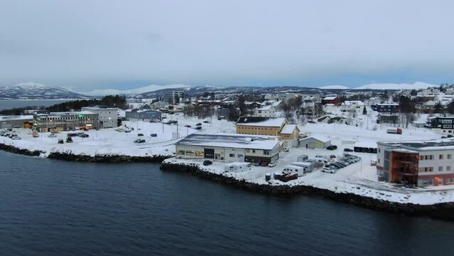 Drone view in Tromso of Finnsnes, a small town full of snow and mountains in the horizon in Norway