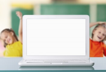 Laptop computer white blank empty screen on teachers table with elementary junior children