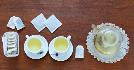 Herbal green tea in paper filter bags. Top view of two cups of hot herbal tea with medicinal herbs chamomile, calendula, rosemary. Traditional treatment for seasonal colds. Flat lay, copy space