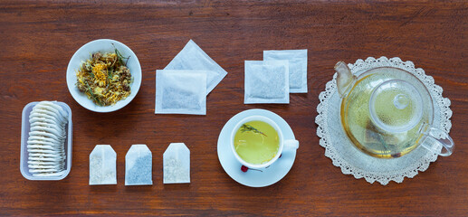 Different types of medicinal herbal green tea in paper filter bags and cup of hot tea with...