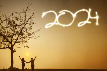 Silhouette of happy couple holding hands together while celebrating new year of 2024 in the park