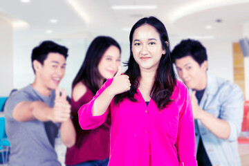 Young female with Group of college students looks happy while showing thumbs up