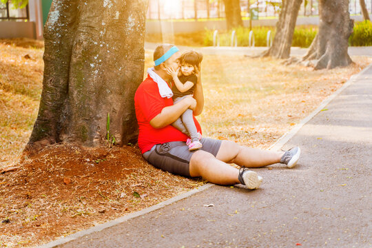 Cute picture of overweight father kissing his daughter in the park