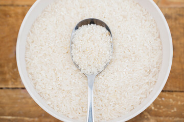 Closeup shot of Spoon of white rice grain on top of white rice grain in a bowl