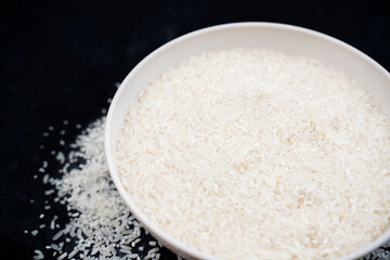 Healthy food. Bowl of white rice grains on black background