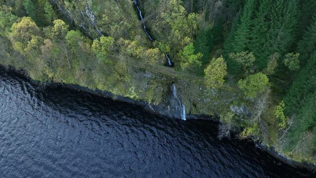 Water stream passing below wid narrow countryside road at autumn, aerial Norway