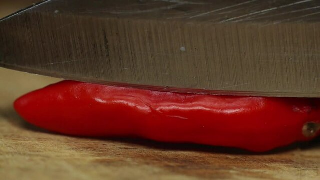 slow motion on Chopping the cayenne pepper on a wooden cutting board.
