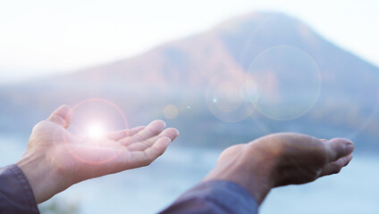 Hand receive light background. With open hands gesture of person on top mountain soft blue color...