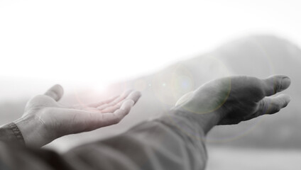 Hands receive lights in black and white background. Hand reaching out. Hope and faith, spiritual backgrounds concept. Receiving blessings. Surrender to God concepts. - obrazy, fototapety, plakaty