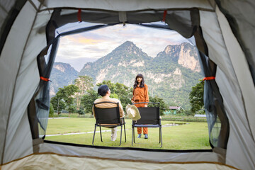 Looking out from the inside of the tent, Amazing sunrise with mountains and Asian couple with two...