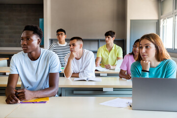 Multiracial group of college students in classroom listening to lecture with interest. Highschool...