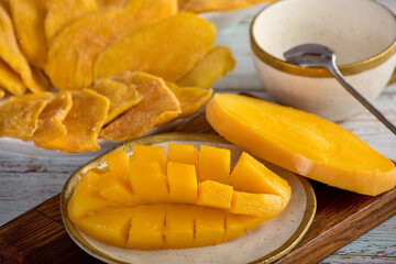 Candied mango slices laid out on a plate and chopped ripe mango pulp on a nice plate. Healthy delicious summer breakfast or a snack of tropical fruits