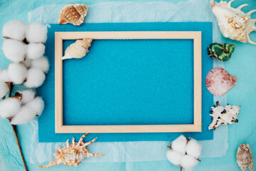 Fototapeta na wymiar Summer composition. Different shells and a wooden frame on a blue background. Top view, a place to copy. The concept of rest and vacations. Wooden frame.