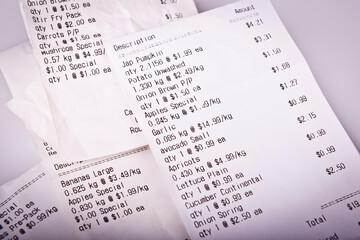 Pile of generic grocery receipts with costs shown in shallow focus for cost of living concept - obrazy, fototapety, plakaty