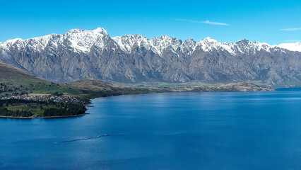 Fototapeta na wymiar Drone panoramic view of the bays and inlets at Queenstown town at the southern end of Lake Wakatipu with a backdrop of the snow capped Remarkables Mountain range
