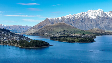 Drone panoramic view of the bays and inlets at Queenstown town at the southern end of Lake Wakatipu with a backdrop of the snow capped Remarkables Mountain range