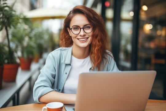 Smiling woman working on laptop and looking at camera