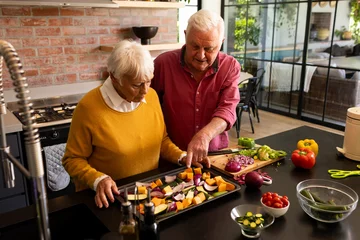 Gordijnen Happy caucasian senior couple preparing fresh vegetables in sunny kitchen, copy space © wavebreak3