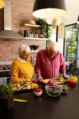  Happy caucasian senior couple preparing chopped vegetables in sunny kitchen, copy space © WavebreakMediaMicro