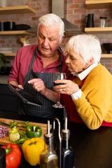  Happy caucasian senior couple preparing vegetables, drinking wine and using tablet in kitchen © wavebreak3