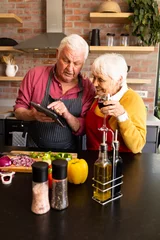  Happy caucasian senior couple preparing vegetables, drinking wine and using tablet in kitchen © WavebreakMediaMicro